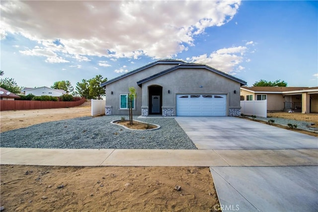 single story home featuring stucco siding, driveway, stone siding, fence, and an attached garage