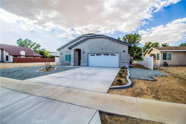 ranch-style home featuring fence, a garage, driveway, and stucco siding