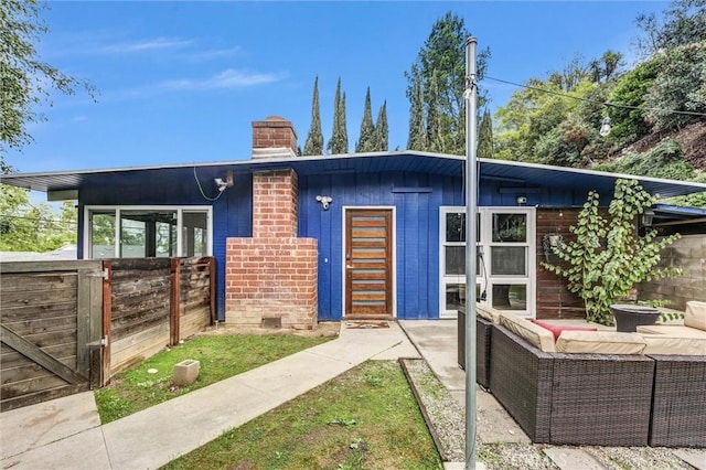 mid-century modern home with fence and a chimney