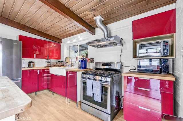 kitchen with red cabinetry, beam ceiling, a sink, range hood, and appliances with stainless steel finishes