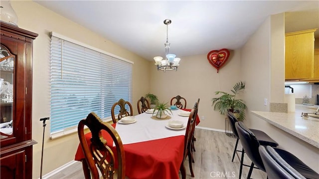 dining area with baseboards, light wood-type flooring, and an inviting chandelier