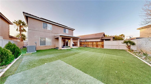 back of property with stucco siding, a yard, central AC, and a fenced backyard