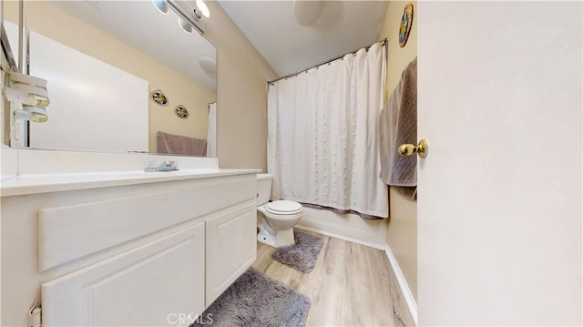 bathroom with a shower with curtain, toilet, wood finished floors, baseboards, and vanity