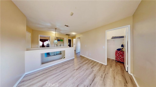 unfurnished living room featuring wood finished floors, visible vents, and baseboards