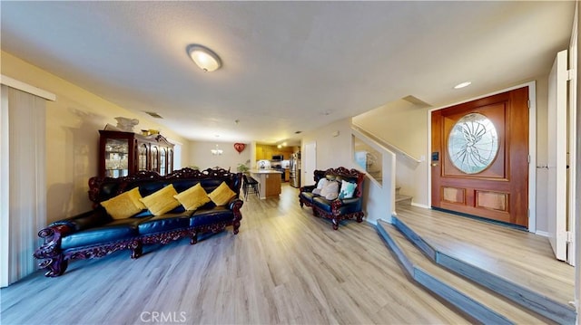 living room featuring stairs, visible vents, light wood-type flooring, and baseboards