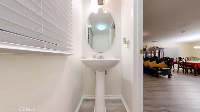 bathroom featuring baseboards, an inviting chandelier, and wood finished floors