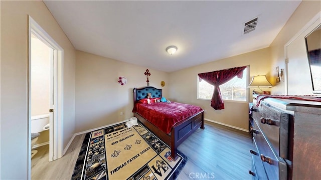 bedroom with visible vents, baseboards, and wood finished floors