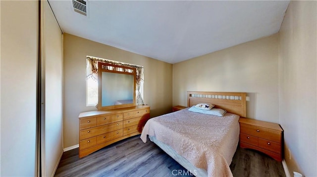 bedroom with wood finished floors, visible vents, and baseboards