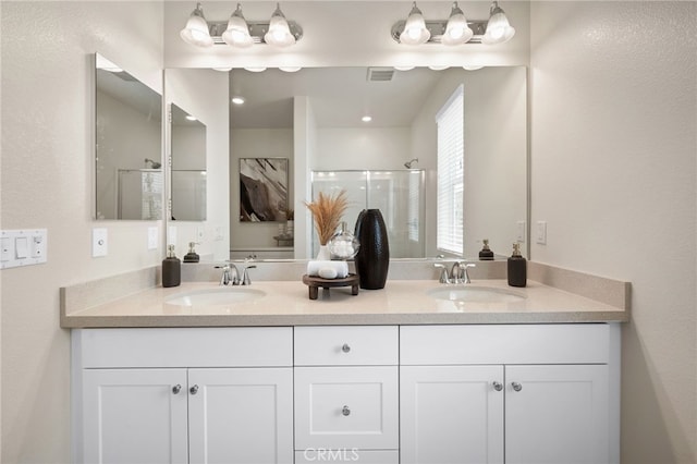 full bath with a shower stall, double vanity, visible vents, and a sink