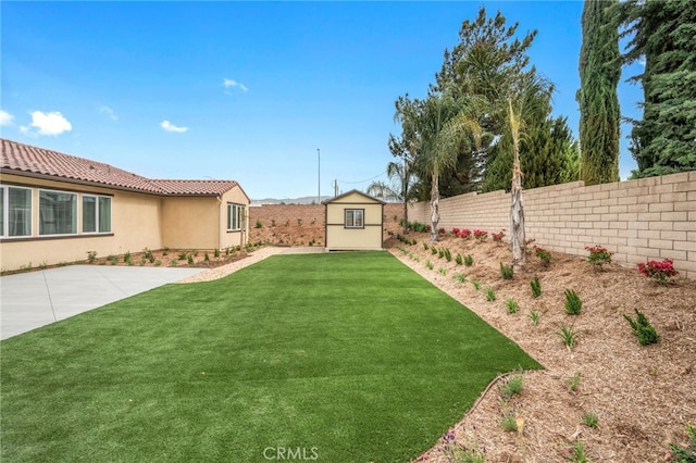 view of yard with an outbuilding, a storage unit, a fenced backyard, and a patio area