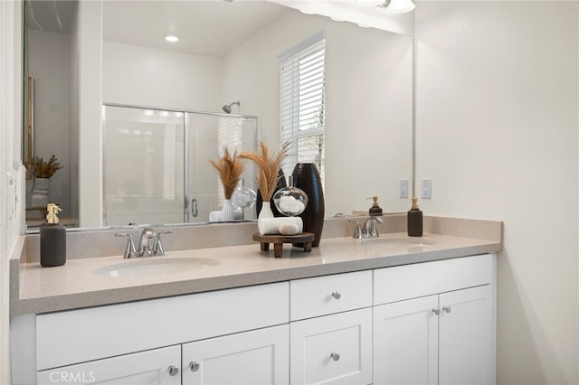 full bathroom with double vanity, a stall shower, and a sink