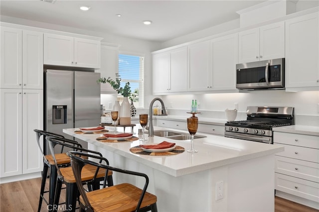 kitchen with a sink, white cabinets, light wood-type flooring, and stainless steel appliances