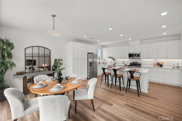 dining space with recessed lighting and light wood-type flooring