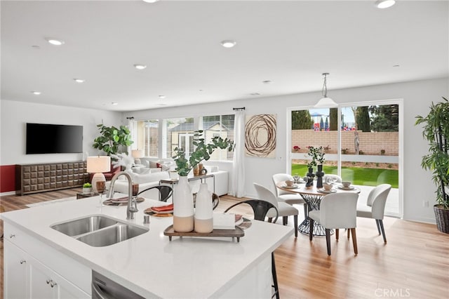 kitchen with light wood finished floors, a sink, recessed lighting, white cabinets, and light countertops