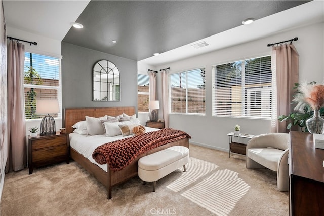 bedroom featuring visible vents, light carpet, multiple windows, and baseboards