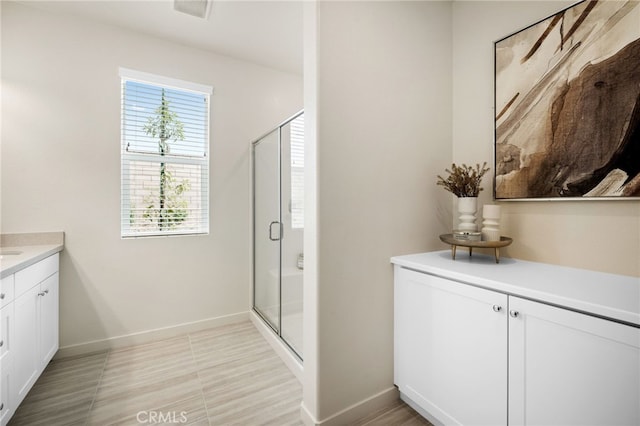 bathroom featuring a stall shower, vanity, and baseboards