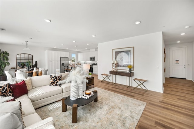 living room with recessed lighting, light wood-type flooring, and visible vents