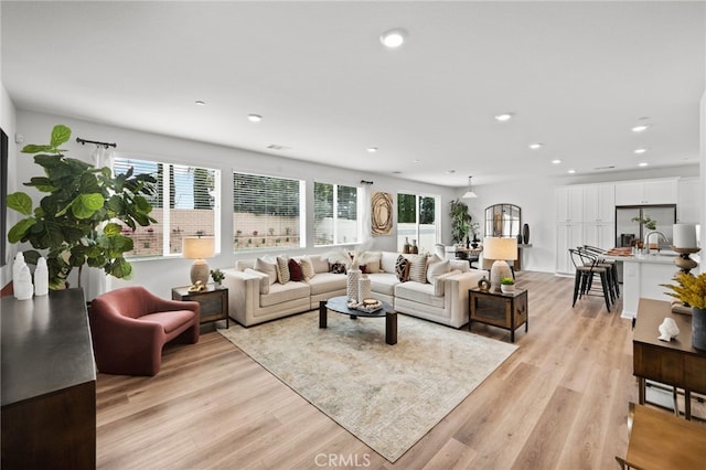 living room with recessed lighting, a healthy amount of sunlight, and light wood finished floors