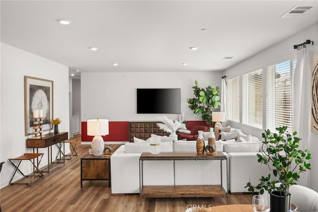 living room with recessed lighting, wood finished floors, and visible vents