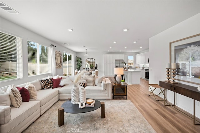 living room with recessed lighting, light wood-style floors, and visible vents