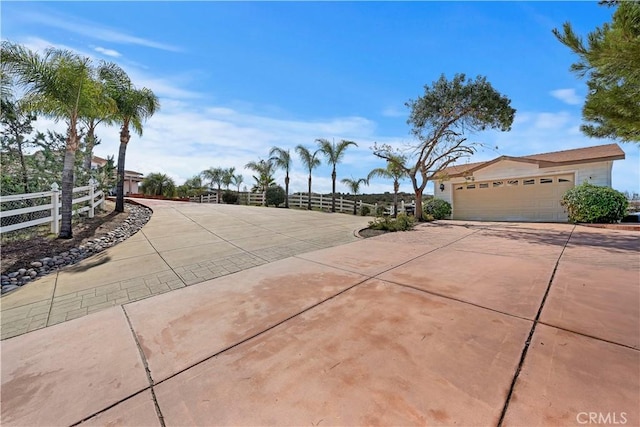 view of community with an attached garage, fence, and driveway