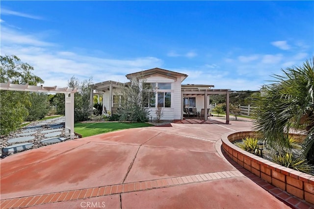 rear view of house featuring a lawn, concrete driveway, a pergola, and a patio area