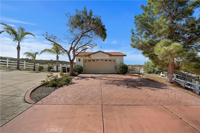 view of front of house featuring an attached garage, decorative driveway, and fence