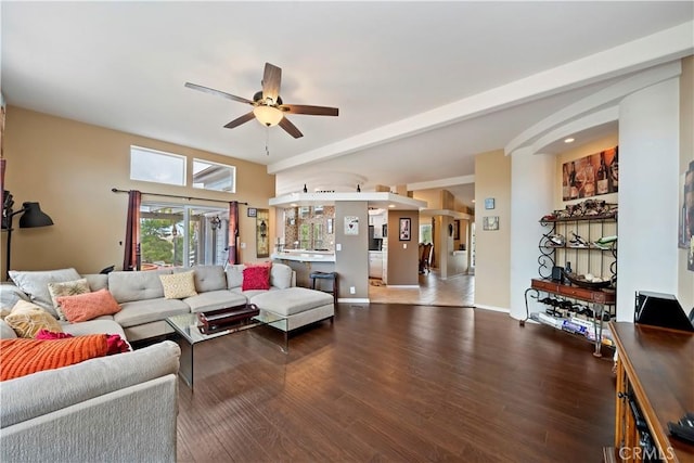 living room featuring baseboards, wood finished floors, arched walkways, and ceiling fan