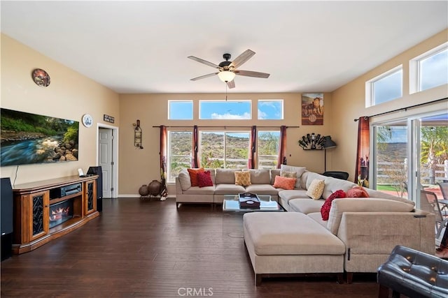 living room with dark wood-type flooring, baseboards, and ceiling fan