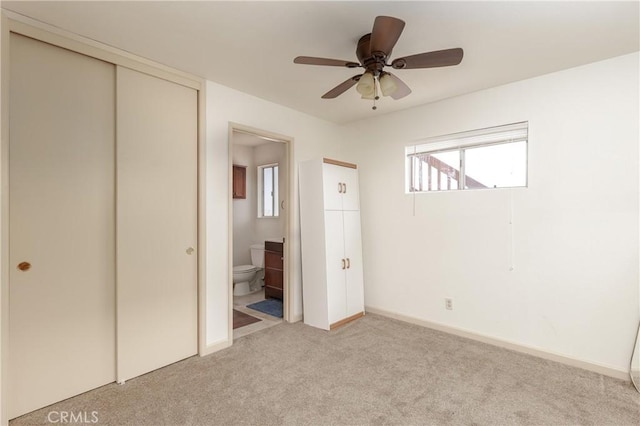 unfurnished bedroom with a ceiling fan, ensuite bath, a closet, baseboards, and light colored carpet