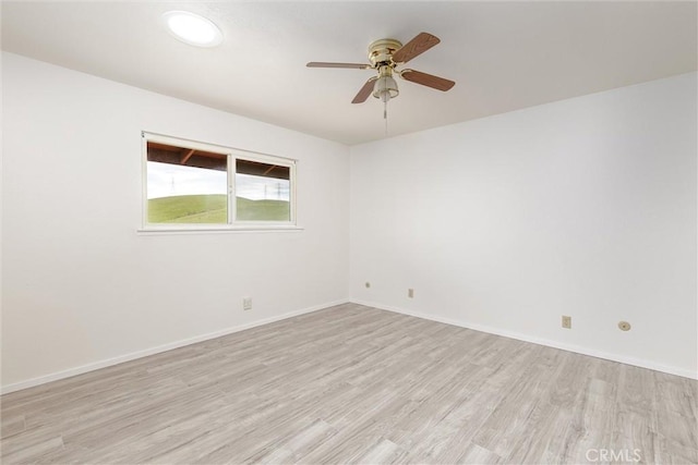 spare room featuring baseboards, a ceiling fan, and light wood finished floors