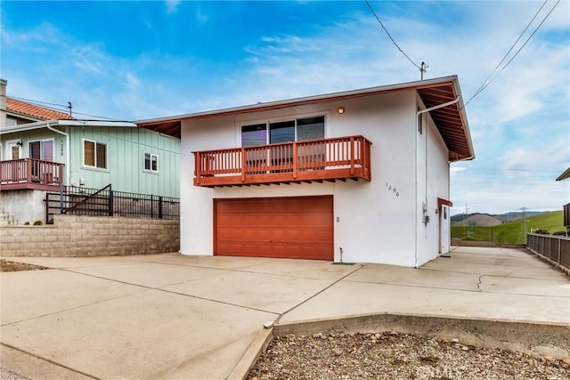 view of front of house with concrete driveway, an attached garage, fence, and stucco siding