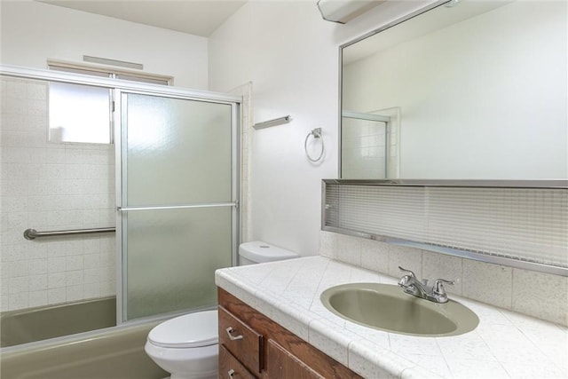 full bath featuring backsplash, toilet, vanity, and shower / bath combination with glass door