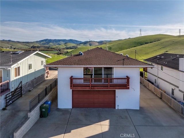 view of front of home with fence, concrete driveway, roof with shingles, stucco siding, and a mountain view