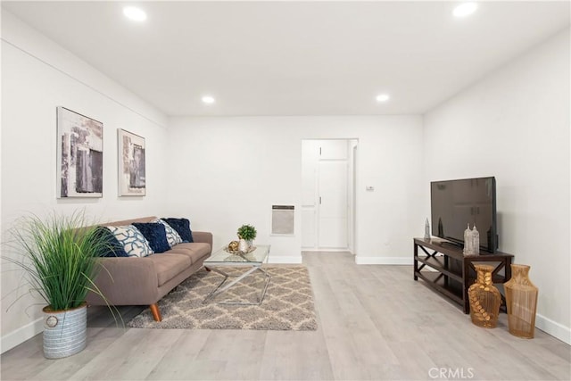 living room featuring recessed lighting, heating unit, baseboards, and light wood-style flooring