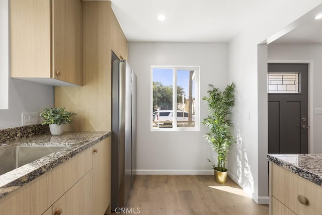11541 Basye St, El Monte, CA 91732 - kitchen with light brown cabinets, baseboards, stone countertops, freestanding refrigerator, and light wood-type flooring