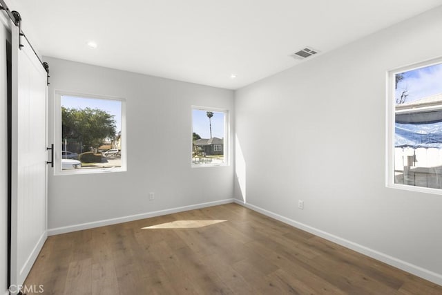 11541 Basye St, El Monte, CA 91732 - unfurnished room featuring plenty of natural light, visible vents, a barn door, and wood finished floors