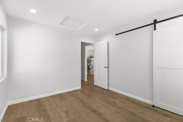 11541 Basye St, El Monte, CA 91732 - unfurnished bedroom featuring wood finished floors, recessed lighting, a barn door, baseboards, and attic access