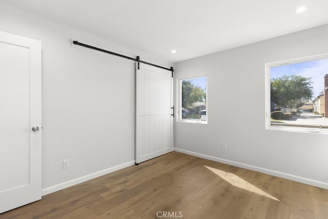 11541 Basye St, El Monte, CA 91732 - unfurnished bedroom featuring a barn door, recessed lighting, wood finished floors, and baseboards