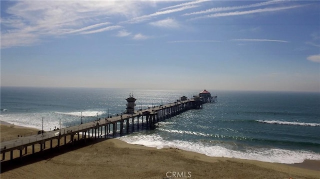 dock area with a pier, a water view, and a view of the beach