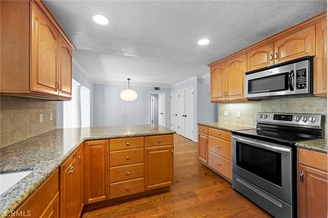 kitchen with a peninsula, stainless steel appliances, crown molding, and dark wood-style flooring