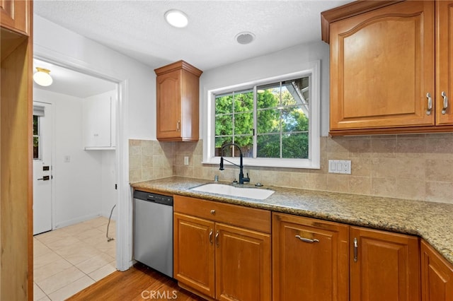 kitchen featuring dishwasher, brown cabinets, tasteful backsplash, and a sink