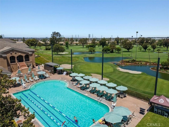 community pool featuring a patio area, a water view, a yard, and fence