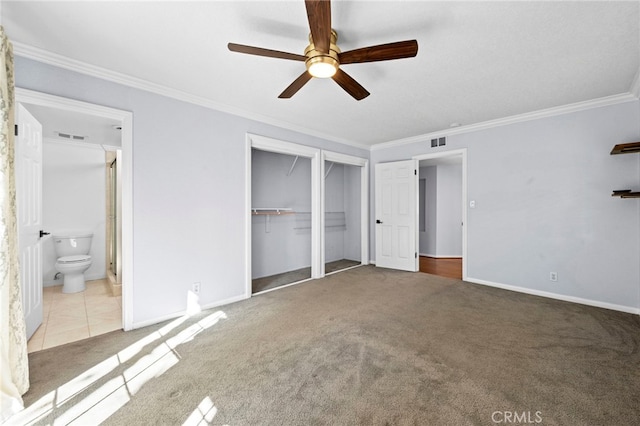 unfurnished bedroom featuring visible vents, ensuite bathroom, carpet, crown molding, and baseboards