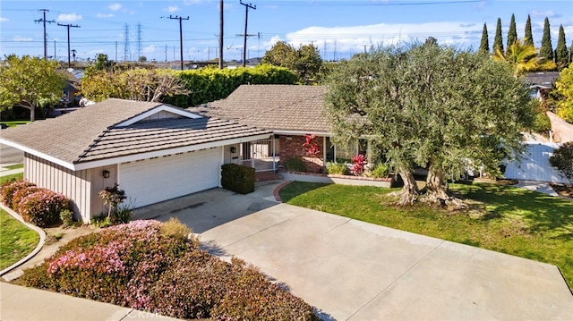 view of front of house featuring a front lawn, concrete driveway, and an attached garage