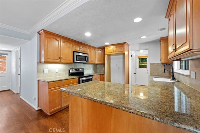 kitchen featuring dark wood-type flooring, a sink, stone countertops, stainless steel appliances, and a peninsula