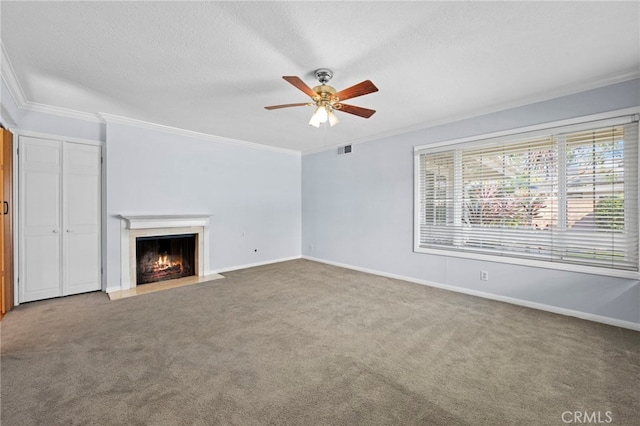 unfurnished living room featuring visible vents, a fireplace with flush hearth, ornamental molding, a ceiling fan, and carpet