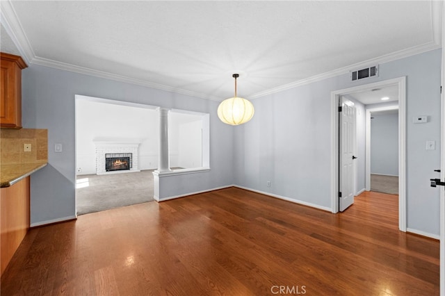 unfurnished living room with visible vents, a brick fireplace, dark wood finished floors, and crown molding