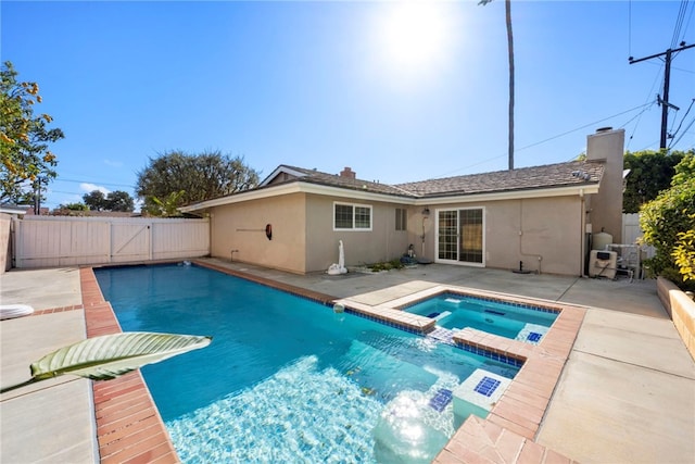 view of pool featuring a patio, fence, a pool with connected hot tub, and a gate