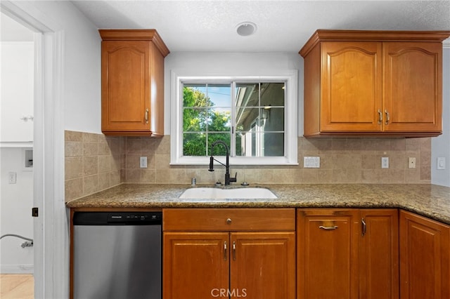 kitchen with brown cabinetry, decorative backsplash, dishwasher, and a sink